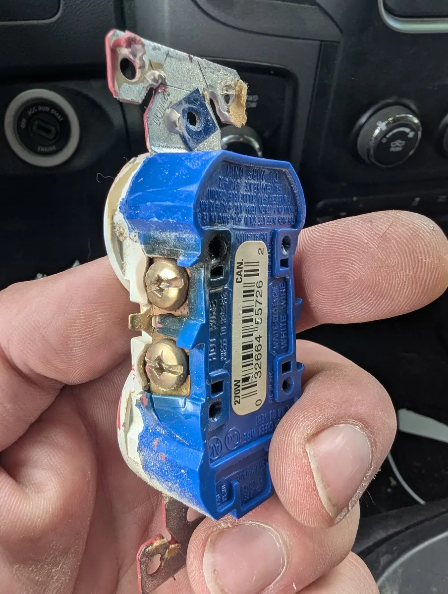Side view of the failed receptacle showing charring at the mounting strap where the internal contacts burned out